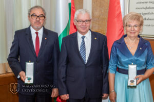 A fotón a két díjazott és a legfőbb ügyész állnak egymás mellett a magyar zászló előtt, a díjazottak kezében a díj.