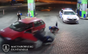 Képrészlet a videóból, ahogy egy férfi elsodorja a benzinkúton a rendőrt és a polgárőrt autójával